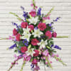 Standing floral spray with pink roses, white lilies, and purple accents