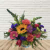 Colorful bouquet with sunflowers, roses, and gerbera daisies in a glass vase