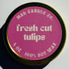 Round candle tin with a pink label reading fresh cut tulips