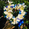Heart-shaped floral wreath with white lilies, cream roses, and blue ribbon accents