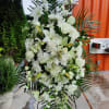 White funeral spray with lilies, roses, and chrysanthemums on a stand