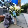 Bouquet of white and pale yellow flowers in a decorated bottle with a teddy bear and baby balloon