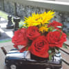 Red roses and yellow sunflowers arranged in a black truck-shaped vase