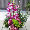 Tall orchid and carnation arrangement in a dark green container
