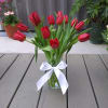 Red tulips in a clear glass vase tied with a white ribbon