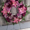 Pink and purple floral wreath on a black stand