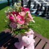 Pink bouquet in a vase beside a plush pink unicorn