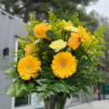 Yellow flowers and roses arranged in a clear glass vase.