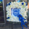 Square floral wreath with white and blue flowers around a Greek crest