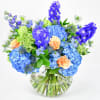 Blue and peach flower arrangement in a clear glass vase