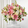 Pink lilies and cream roses in a white pedestal vase
