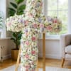 Large floral cross covered in white and pink blooms on a stand