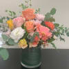 Mixed bouquet of pastel flowers in a green glass vase