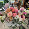 Mixed pastel bouquet with roses, calla lilies, and other blooms in a white container