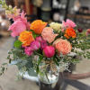 Mixed bouquet of pink, orange, and peach roses in a glass vase