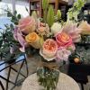 Mixed bouquet of pink roses, lilies, and white blooms in a glass vase