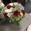 Bouquet of red roses and white flowers with blue hydrangeas in a glass vase