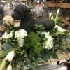 Black dog statue surrounded by white flowers and greenery on a wooden table