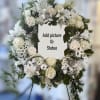 White floral wreath on an easel with a center space for a photo or statue