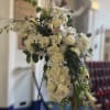 Large white floral cross arrangement on a stand