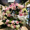 Large pink and white floral standing wreath on an easel with a white bow