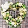 Heart-shaped floral wreath of white and pale green roses on a stand