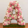 Pink and white floral letter A arrangement on a moss base