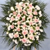 Large standing spray of pink roses and white flowers framed by palm fronds on a wooden easel.
