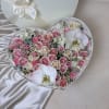 Heart-shaped box filled with pink and ivory roses and white orchids on a satin background