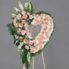Heart-shaped floral wreath of peach and pink roses on a stand