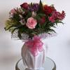 Mixed bouquet of roses and alstroemeria in a wrapped vase with a pink ribbon