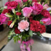 Pink roses and red carnations in a glass vase with a pink ribbon