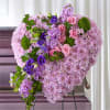 Heart-shaped floral arrangement of pink, purple, and green blooms on an easel