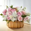Pink and white flowers arranged in a wooden basket