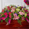 Large floral casket spray with pink lilies, roses, and purple blooms