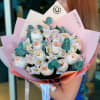 Bouquet of pale pink and white roses wrapped in pink paper