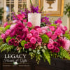 Pink roses and purple mums arranged in a white vase with greenery