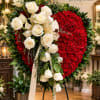 Heart-shaped floral standing spray with white roses and red blooms on a stand