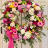 Heart-shaped floral wreath on a stand with pink, white, and yellow blooms
