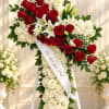 Standing floral cross of red and white roses with lilies on an easel