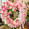 Heart-shaped pink and white rose wreath with a sheer ribbon bow