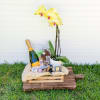 Yellow orchid in a pot with champagne and chocolates on a wooden tray