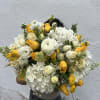 Large bouquet of white and yellow flowers held in front of a wall
