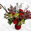 Red floral arrangement in a red vase with gold ornaments and branches