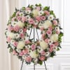 Pink and white floral wreath on a black stand