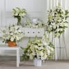 White floral funeral arrangements with lilies and roses in vases and stands
