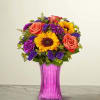 Bouquet of sunflowers, roses, and purple flowers in a pink vase