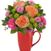 Peach roses and pink flowers arranged in a red mug