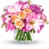 Pink and peach flowers arranged in a clear glass vase