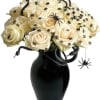 Cream roses in a black vase with decorative spiders and snakes